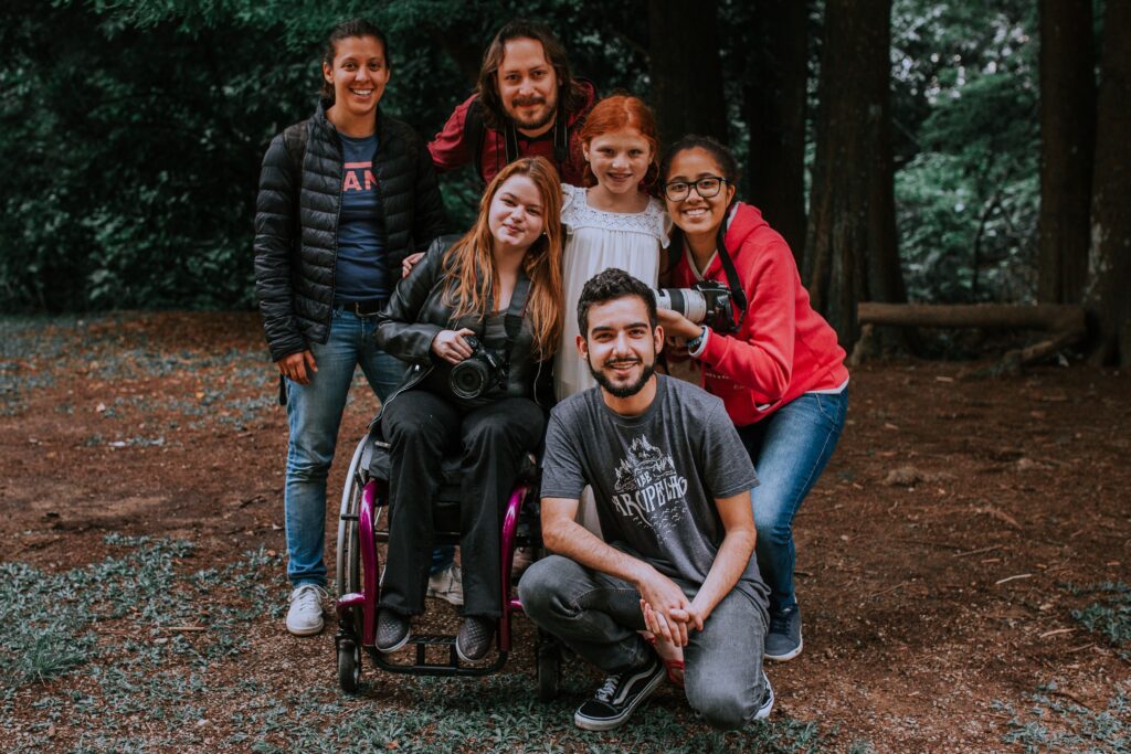 pexels-photo-13872097-13872097 Group of friends smiling and posing with a camera in a forest setting, embracing diversity.